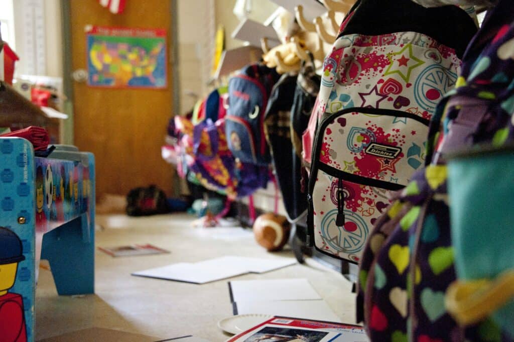 Colorful backpacks hanging in a classroom hallway representing My Stuff Bags for children in foster care.
